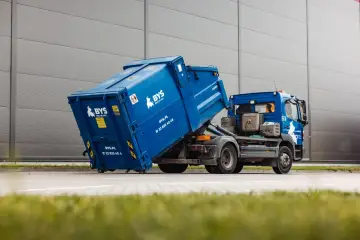 Niebieski kontener na śmieci na ciężarówce BYŚ RECYKLING. Dowiedz się, ile kosztuje kontener na śmieci.